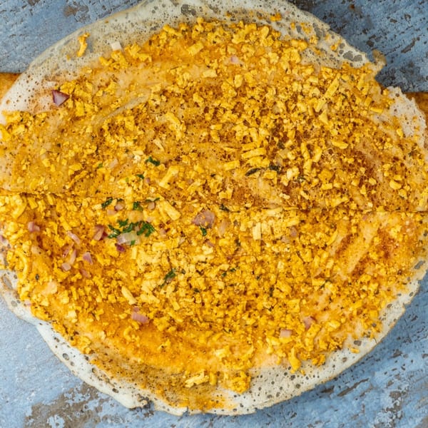 A close-up of a Hello! India paneer dosa, filled with crumbled paneer, onions, and herbs.