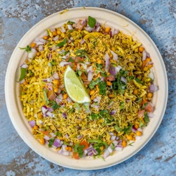 Hello! India's Bhel Puri, a savory Indian snack with puffed rice, vegetables, and a lime wedge.