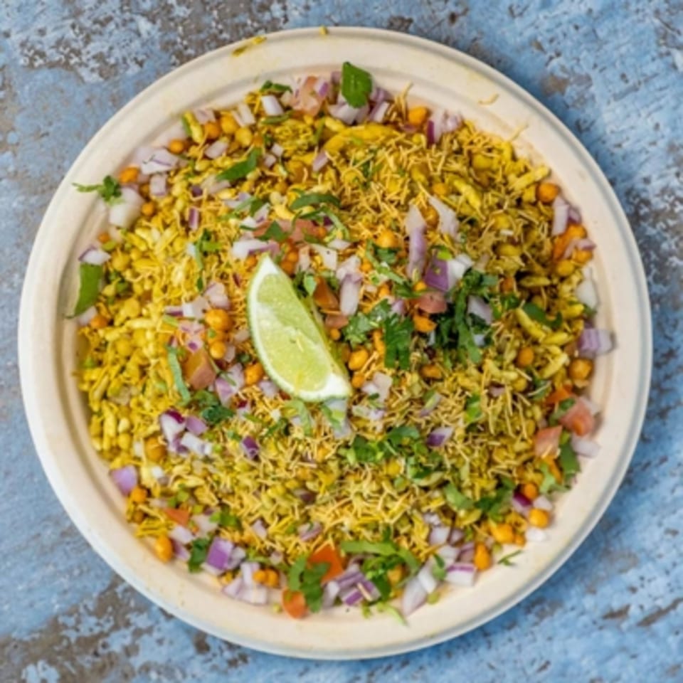Hello! India's Bhel Puri, a savory Indian snack with puffed rice, vegetables, and a lime wedge.