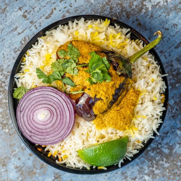 Hello! India's Indian dish with eggplant, rice, red onion, lime, and cilantro, top-down view.