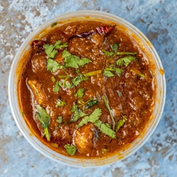 Hello! India's chicken curry, a rich brown stew with cilantro and dried chilies in a plastic container.