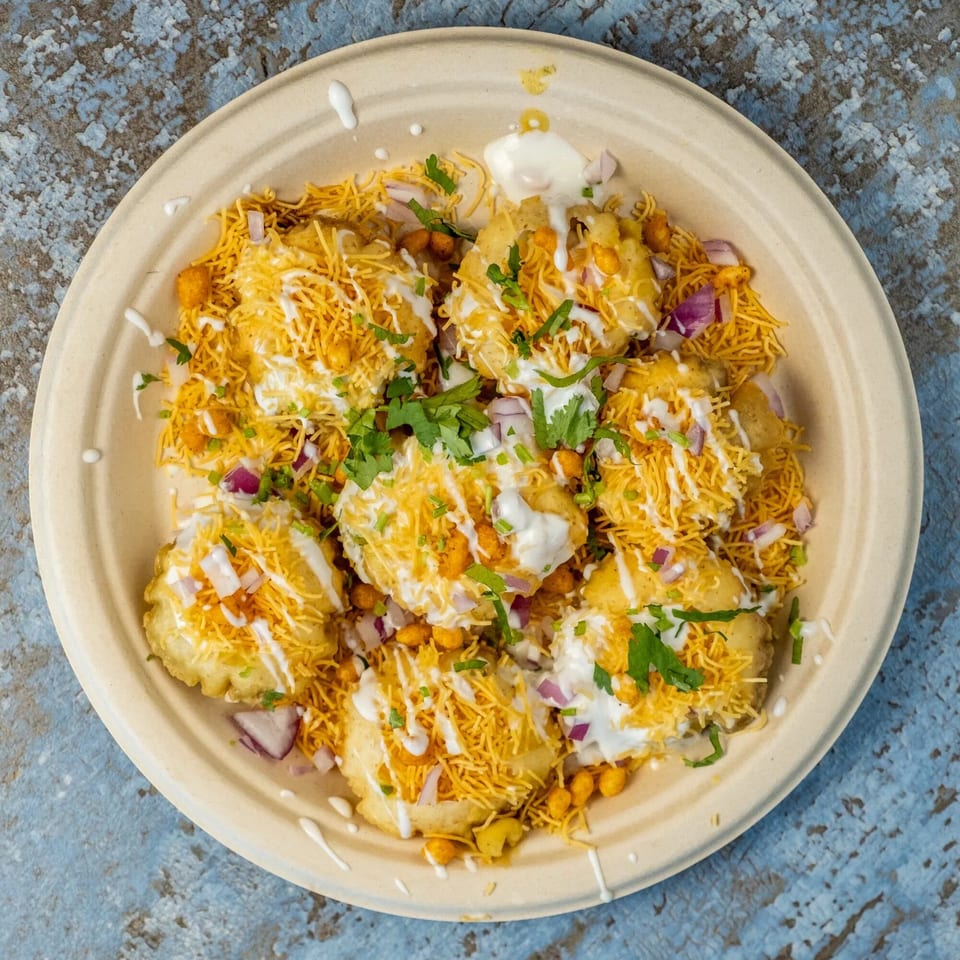 Hello! India's Indian chaat dish with yogurt, sev, chopped onions, and cilantro on a plate.